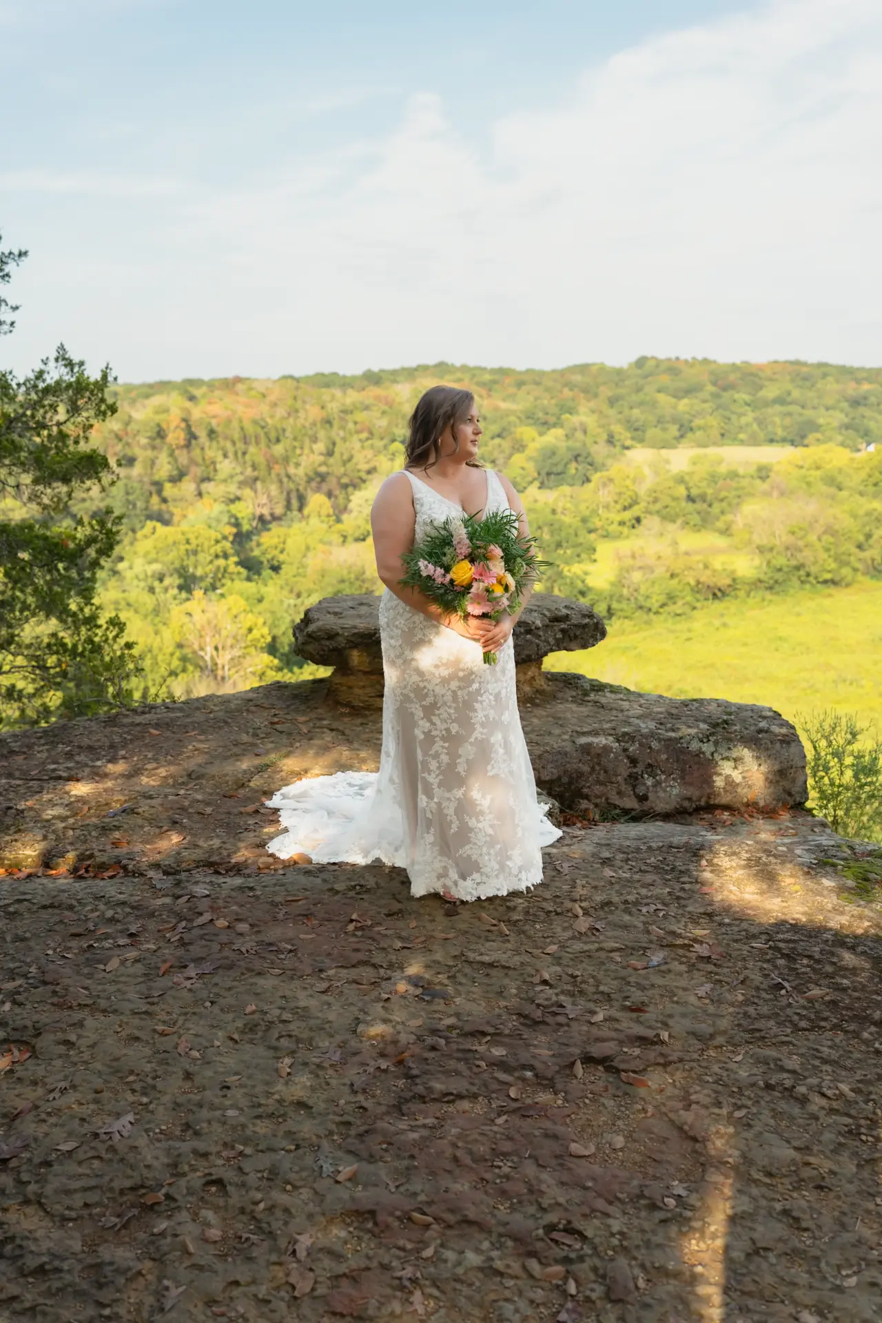 Sam standing on a rocky bluff in her wedding dress in Wheatland, Iowa