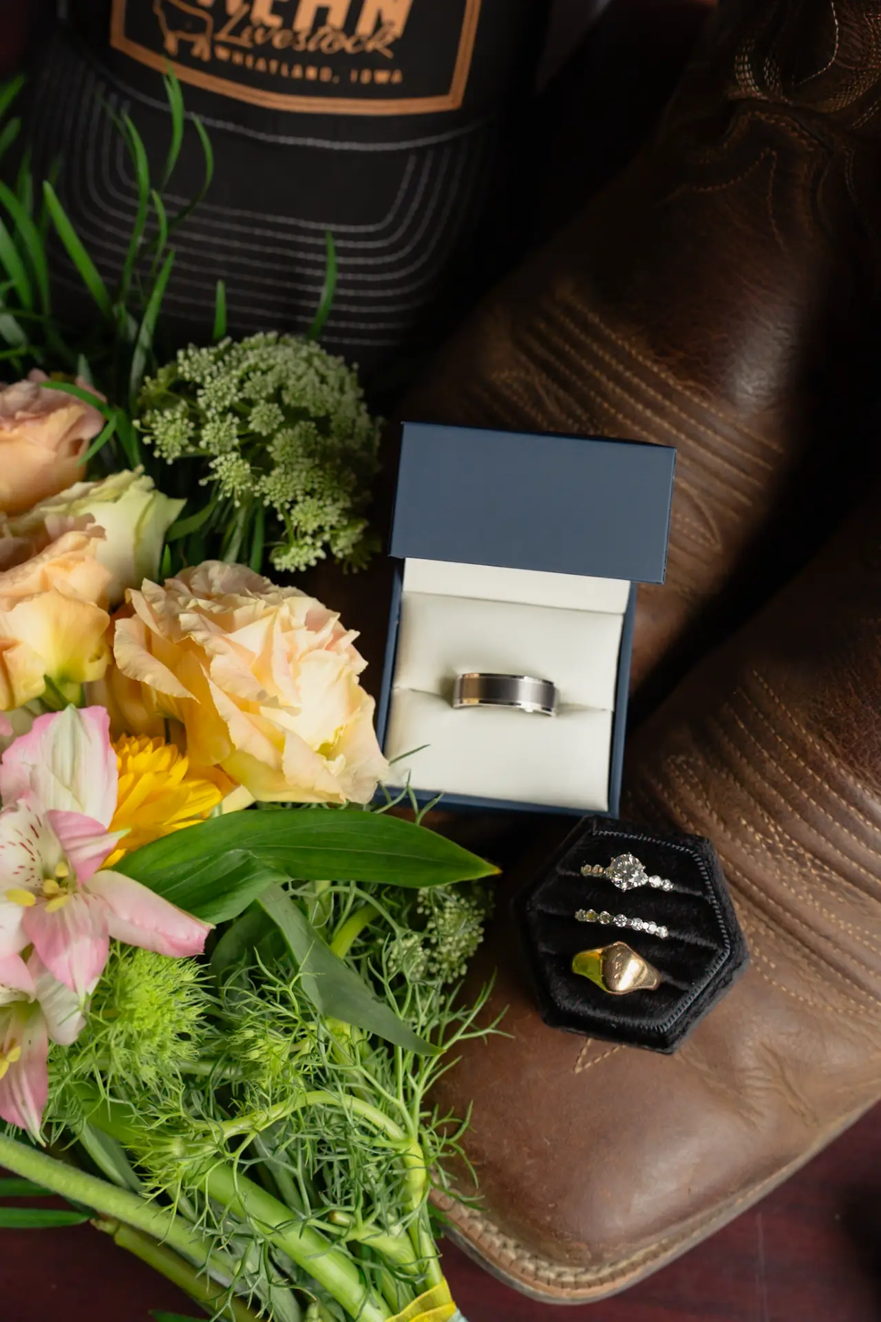 Wedding rings and bouquet resting on leather boots before the ceremony