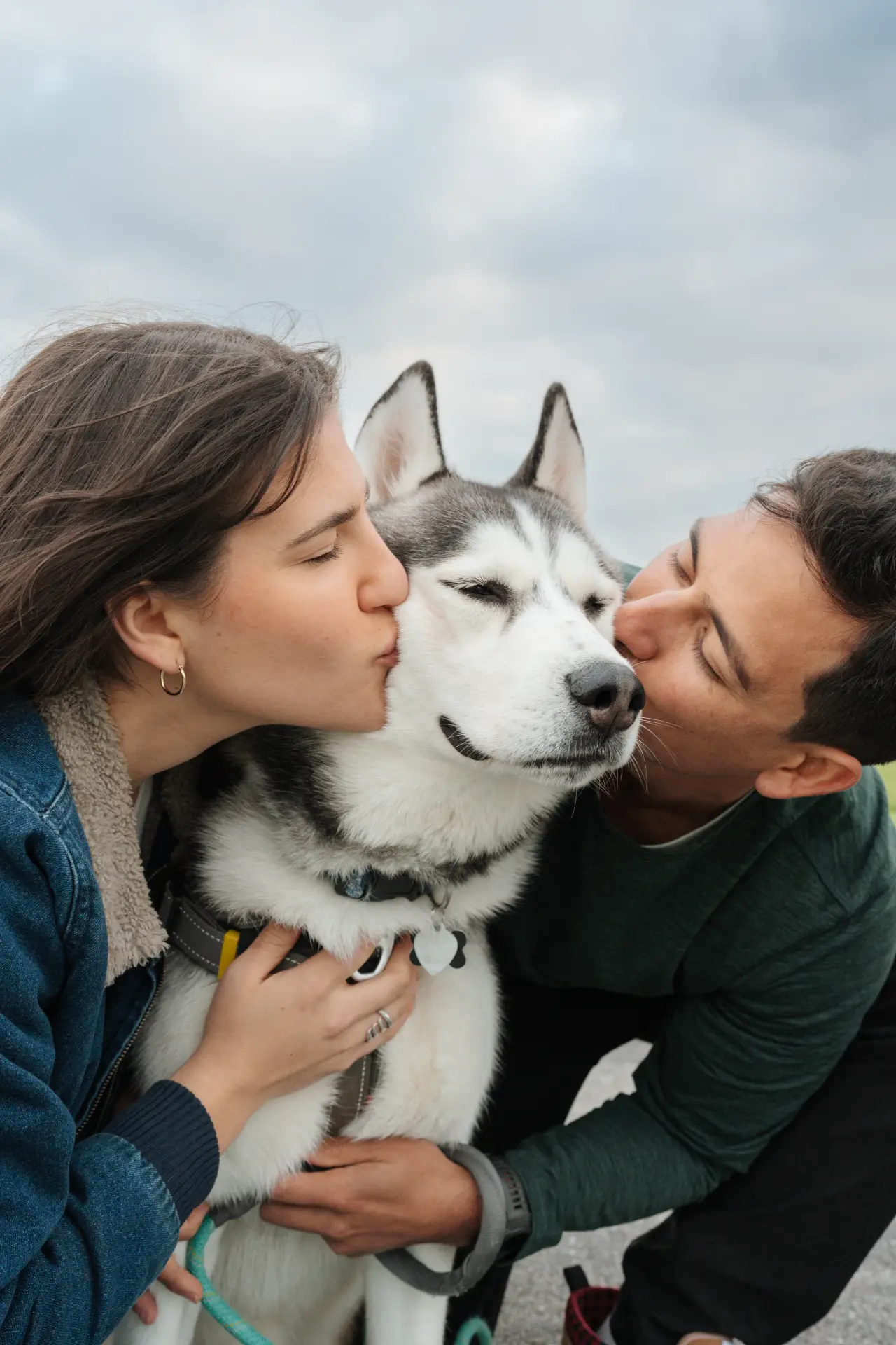 Ticer and Ali kissing their husky on each cheek