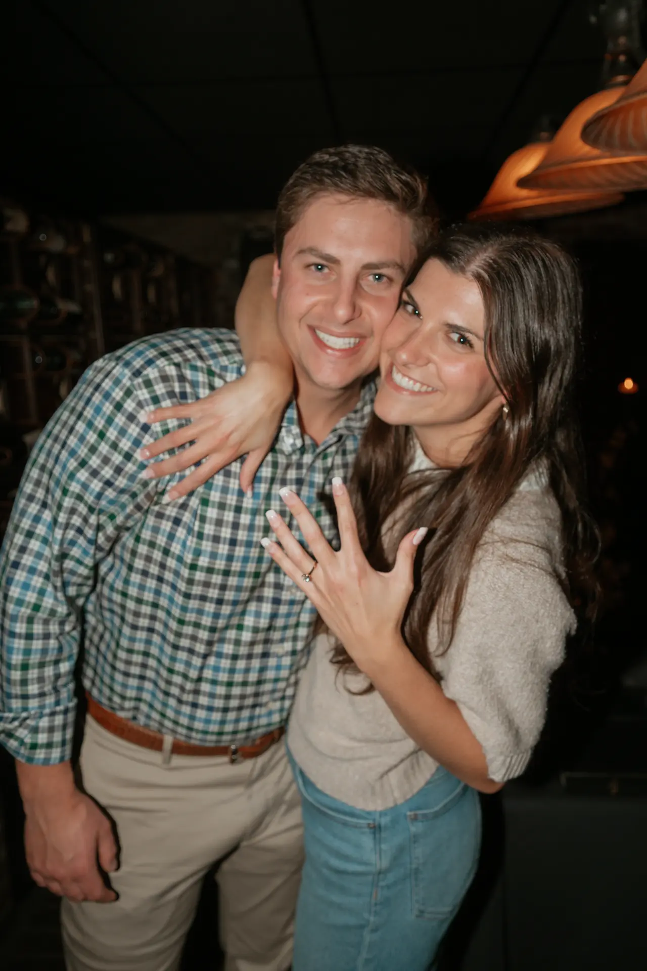 Olivia showing off her engagement ring while hugging Cal in the wine cellar