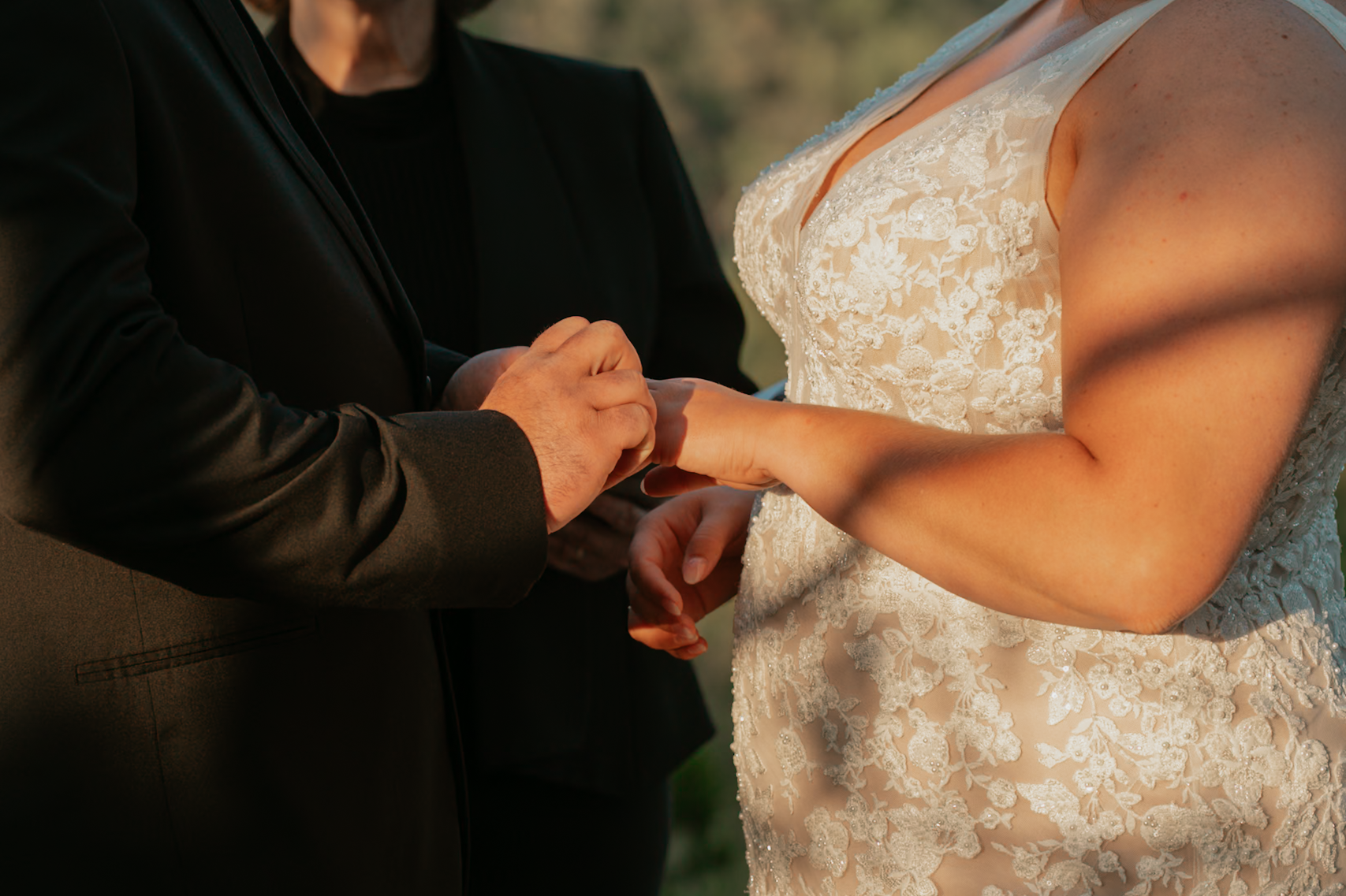 Justin sliding the ring onto Sam's finger during their golden hour ceremony